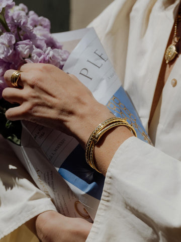 A close up of a woman holding flowers wearing a temple st clair bracelet.