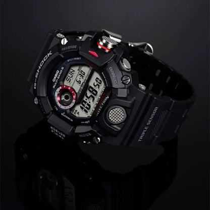 A rugged black Casio G-Shock digital watch with a black strap, silver-tone case details, and small red accents, photographed on a dark reflective studio background. G-SHOCK GW9400-1-2
