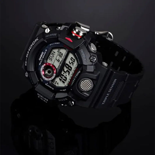 A rugged black Casio G-Shock digital watch with a black strap, silver-tone case details, and small red accents, photographed on a dark reflective studio background. G-SHOCK GW9400-1-2