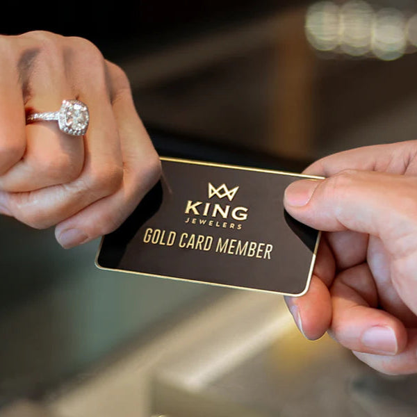 Hand holding a King Jewelers gold card member card with a blurred background